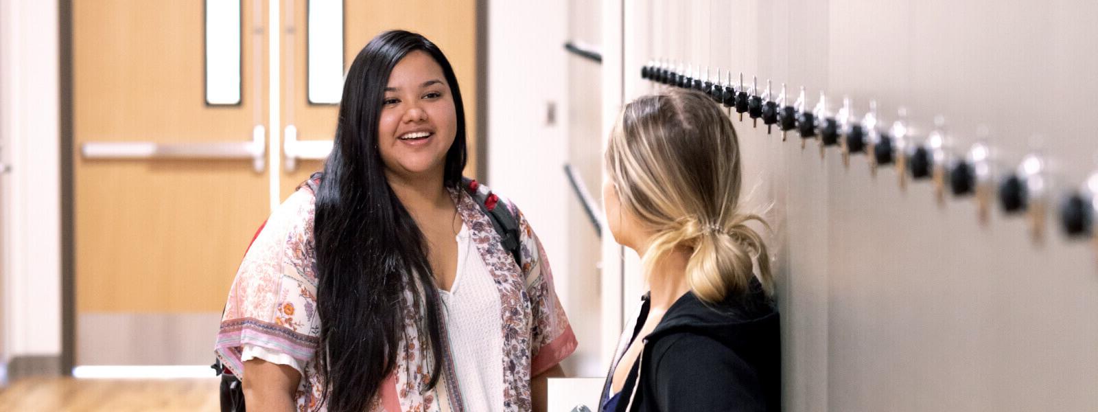 Two students talking in a hallway next to lockers